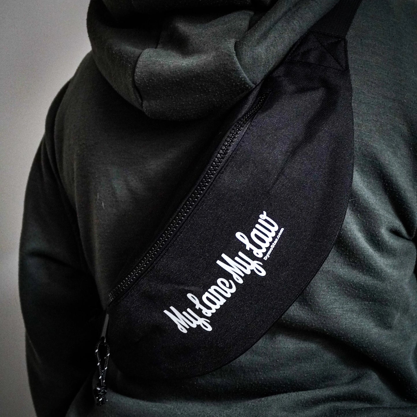 Schwarz gestaltete Bauchtasche für Motorradfahrer mit weißem Firmenlogo „DYMSTR/DymoStar“ und dem Schriftzug „My Lane My Law“ auf der Vorderseite.
