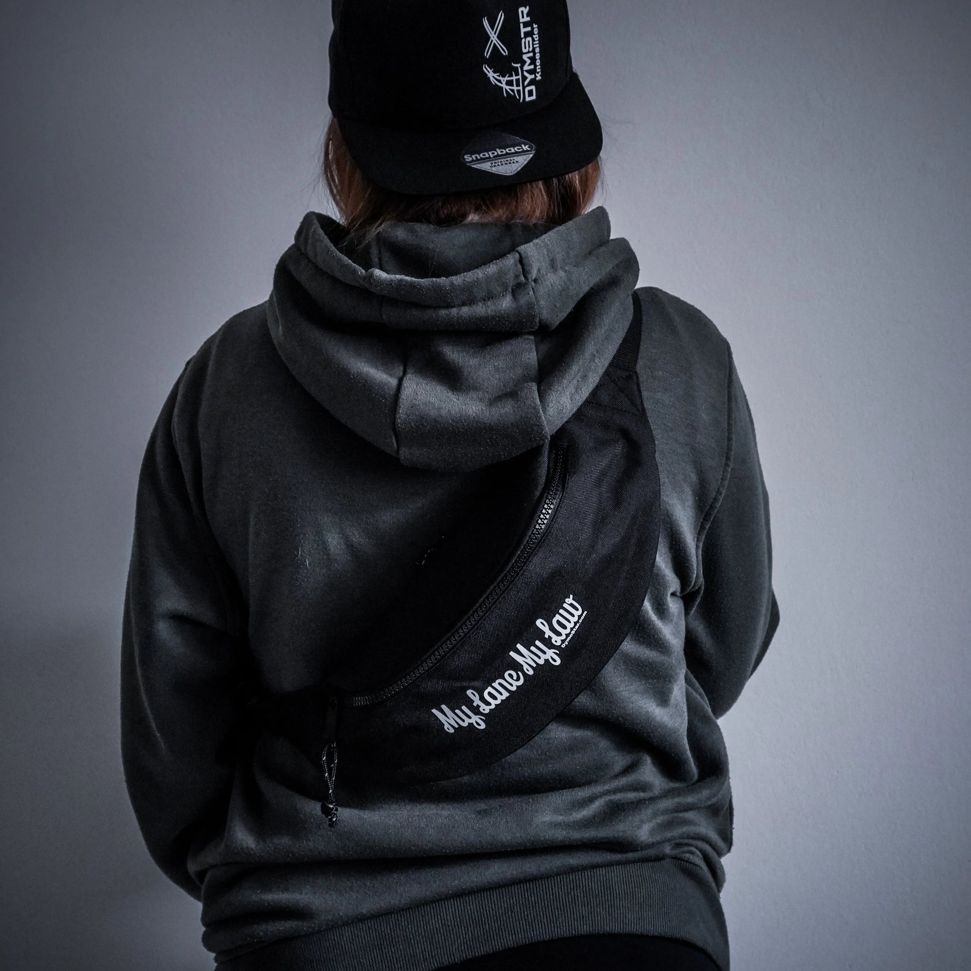 Schwarz gestaltete Bauchtasche für Motorradfahrer mit weißem Firmenlogo „DYMSTR/DymoStar“ und dem Schriftzug „My Lane My Law“ auf der Vorderseite.