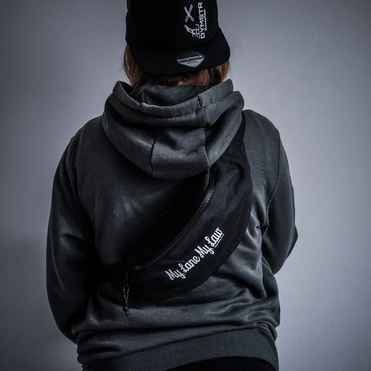 Schwarz gestaltete Bauchtasche für Motorradfahrer mit weißem Firmenlogo „DYMSTR/DymoStar“ und dem Schriftzug „My Lane My Law“ auf der Vorderseite.